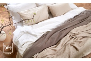 cama con sábanas, plumones y almohadas